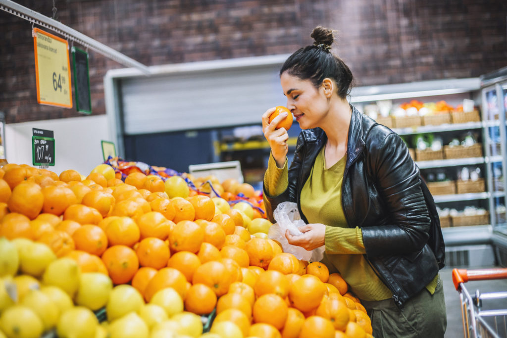 Woman smelling oranges at grocery store