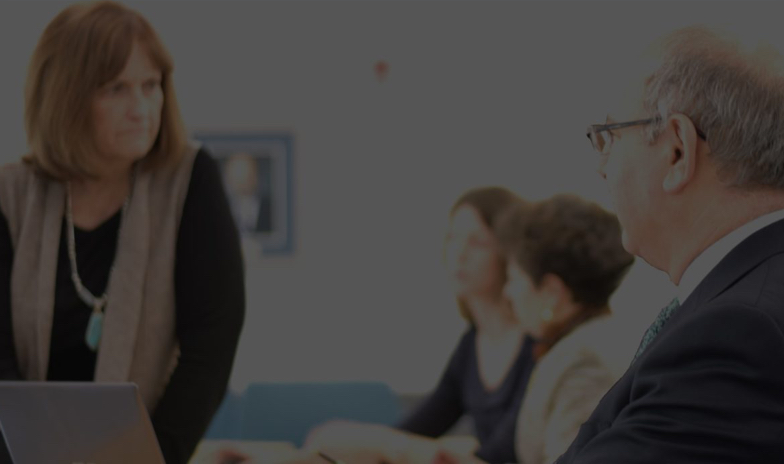 Woman on a laptop at a meeting with others