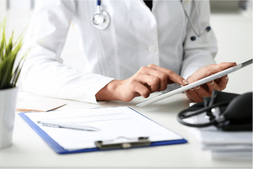 Female doctor in white coat on her desk working on an iPad