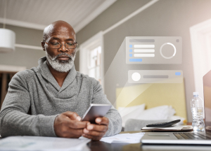 Mid-aged male holding cell phone in a home office setting. Health stats card is popping out from the phone.