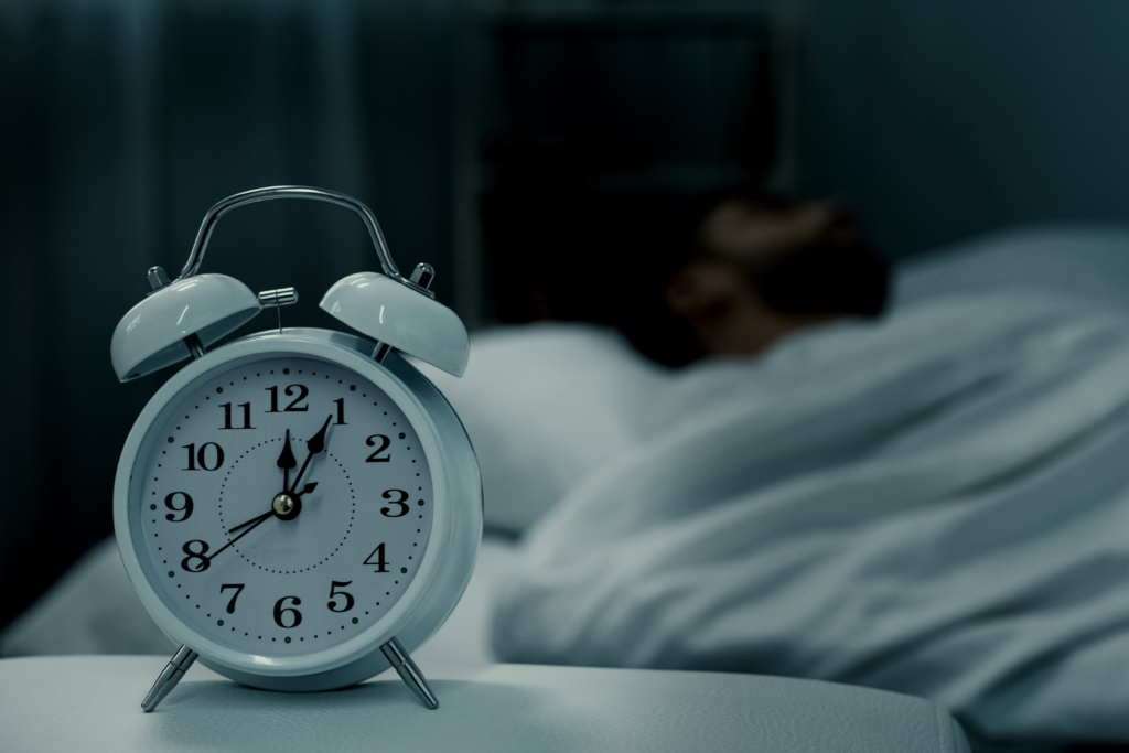 Alarm clock with person in the bed in the distance