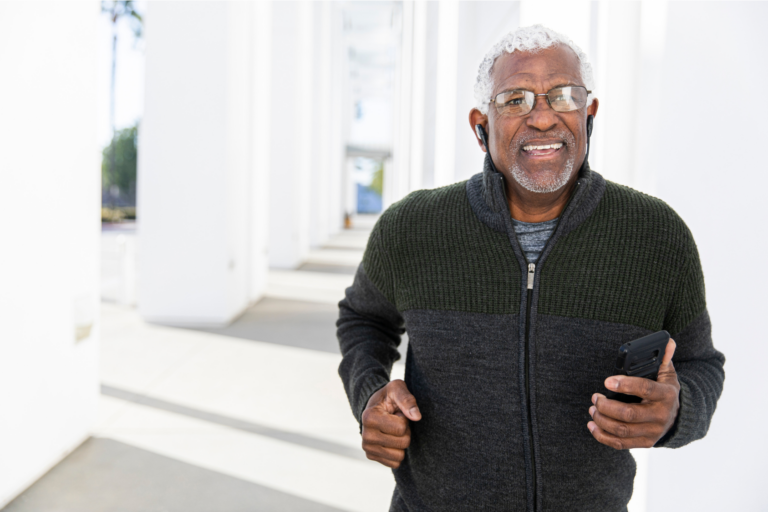 Middle aged man walking while holding cell phone