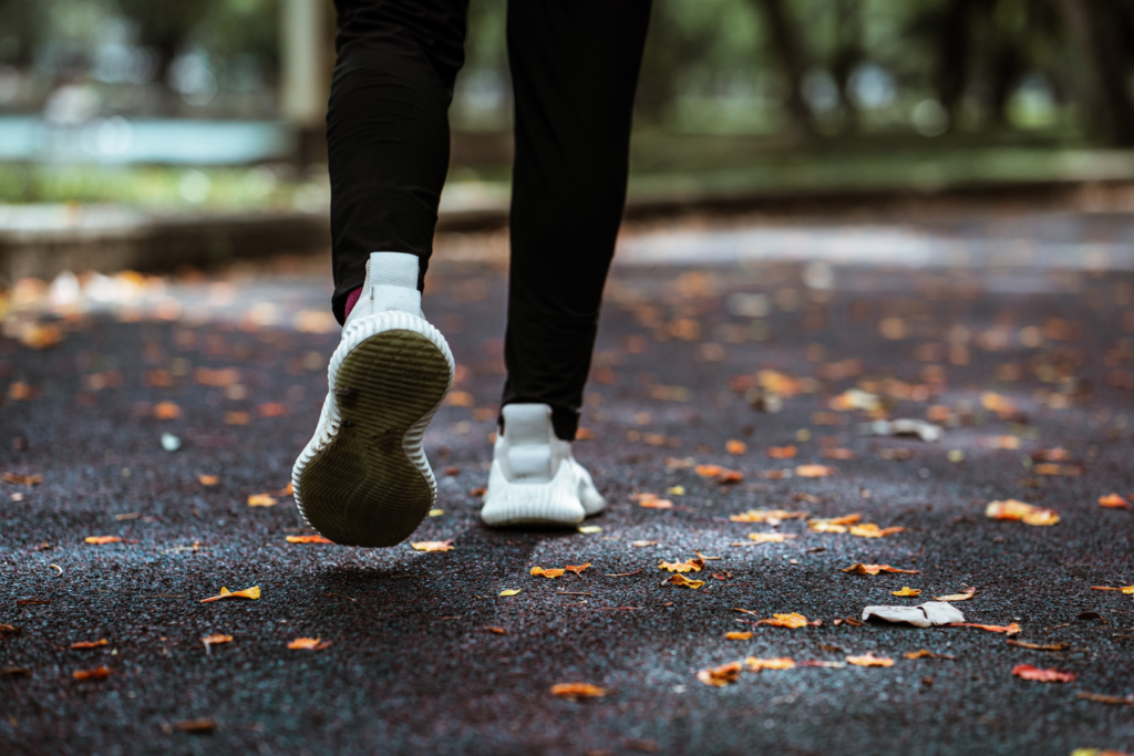Sneakers running on pavement covered in leaves