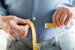 Man measuring his waist with a tape measure.